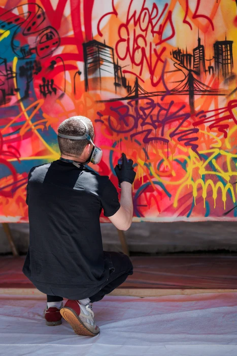 Un artiste effectuant du live painting en direct sur un mur, créant une fresque colorée avec aérosol ou pinceau, dans un environnement urbain ou d'événement professionnel, montrant la maîtrise technique et la créativité artistique caractéristiques du live painting urbain.