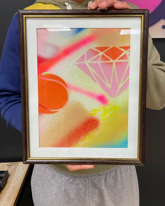 Photographie d'un artiste réalisant une fresque murale lors d'un événement d'entreprise, capturant le moment du live painting avec le pinceau à la main face au mur, dans un contexte professionnel clair avec des participants ou spectateurs visibles, montrant l'interaction entre l'artiste et le public pendant la création artistique en direct.