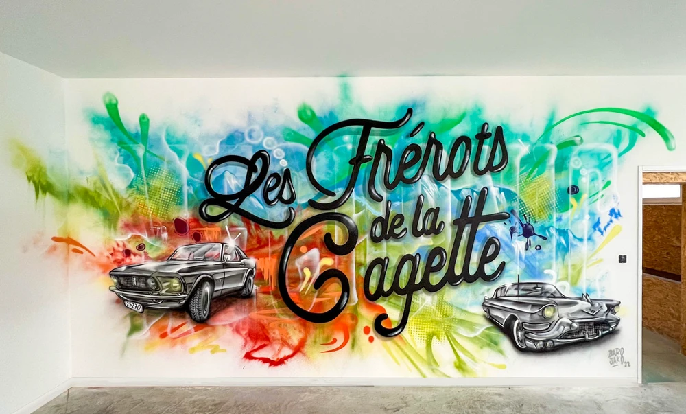 Artiste muraliste professionnel en train de peindre une fresque colorée et géométrique sur un mur blanc ou sur la façade d'un bâtiment commercial. L'artiste est équipé de matériel professionnel (bombes de peinture, brosses, pot de peinture), portant des vêtements de travail pratiques. La scène capture le moment de création, montrant la progression du travail et la maîtrise technique de l'exécution. La composition doit être dynamique et montrer clairement l'acte de création artistique murale, sans texte visible, avec une qualité photographique professionnelle.